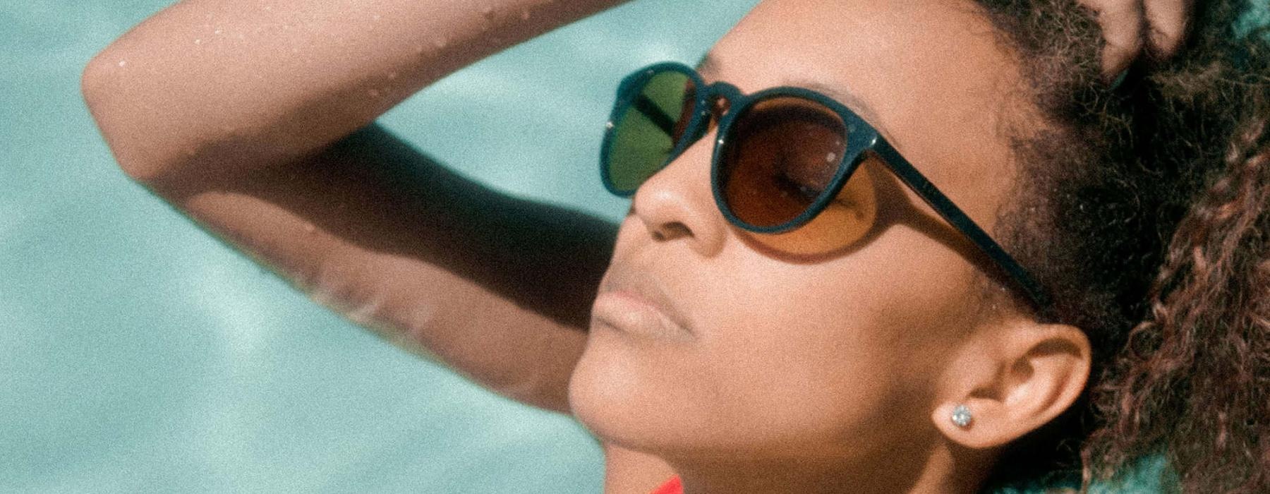 woman wearing sunglasses stands in a pool and basks in the sun